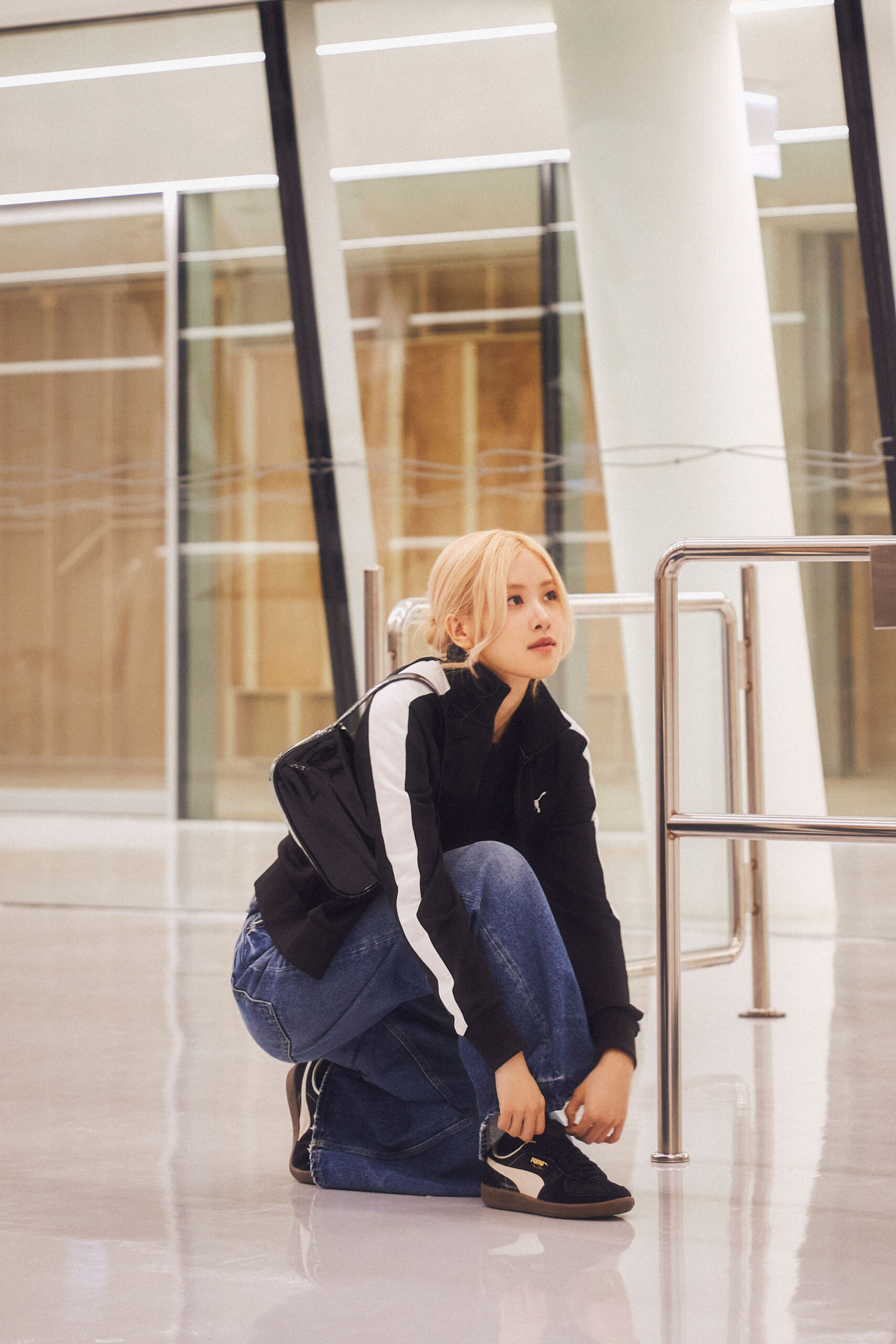 Woman kneels in an airport, tying up a Puma shoe