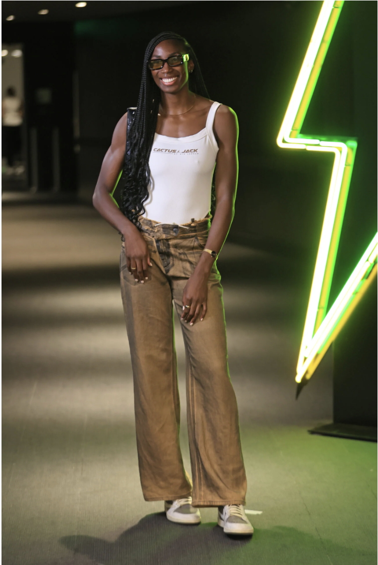 Ezi Magbegor may already be dreaming of Olympic gold…or at least that’s what it seemed when the Seattle Storm star chose brightly colored gold metallic pants as her signature piece to pair with a collaborative Travis Scott WMNS bodysuit and neutral palette Travis Scott x Air Jordan 1 Retro Lows.